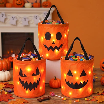 Three orange LED jack-o'-lantern candy buckets glowing indoors