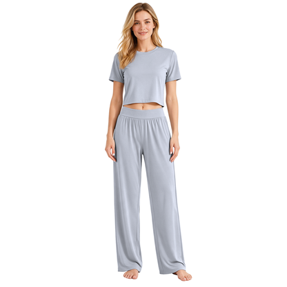 Gray colourway — AI-generated studio image of an adult model wearing the two-piece pyjama set (short cropped crew-neck tee with exposed midriff, wide elastic high-waist wide-leg trousers)