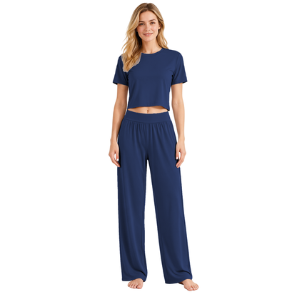 Navy colourway — AI-generated studio image of an adult model wearing the two-piece pyjama set (short cropped crew-neck tee with exposed midriff, wide elastic high-waist wide-leg trousers)